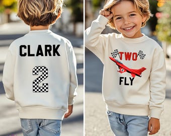 May include: A white sweatshirt with a black checkered number 2 and the name "CLARK" printed on the back. The front of the sweatshirt has a red airplane with the words "TWO FLY" and checkered flags printed on it.