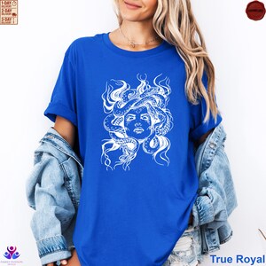 Pode incluir: Camiseta azul True Royal com um gr&aacute;fico branco do rosto de Medusa e cobras. O design &eacute; uma ilustra&ccedil;&atilde;o detalhada da figura mitol&oacute;gica. A camisa &eacute; um estilo cl&aacute;ssico de gola redonda.
