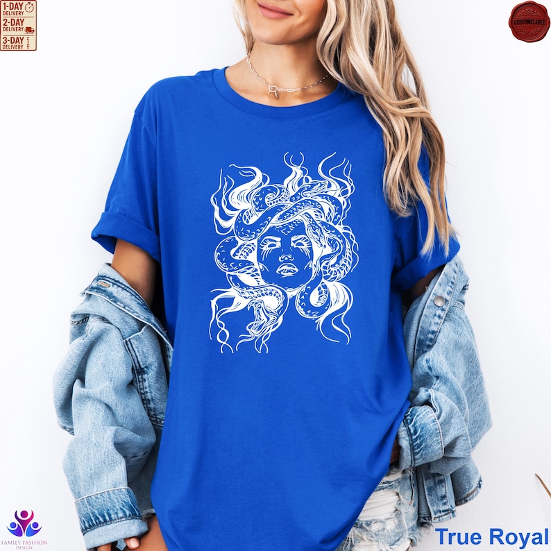 Pode incluir: Camiseta azul True Royal com um gr&aacute;fico branco do rosto de Medusa e cobras. O design &eacute; uma ilustra&ccedil;&atilde;o detalhada da figura mitol&oacute;gica. A camisa &eacute; um estilo cl&aacute;ssico de gola redonda.