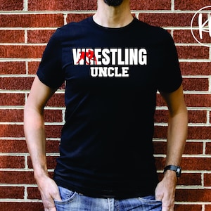 May include: A black t-shirt with white text that reads "Wrestling Uncle" and a red graphic of a wrestler.