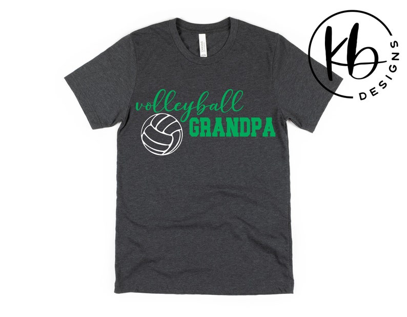 K&ouml;nnte beinhalten: Ein dunkelgraues T-Shirt mit dem Text "Volleyball Grandpa" in gr&uuml;ner und wei&szlig;er Schrift. Eine wei&szlig;e Volleyballgrafik befindet sich mittig &uuml;ber dem Text.