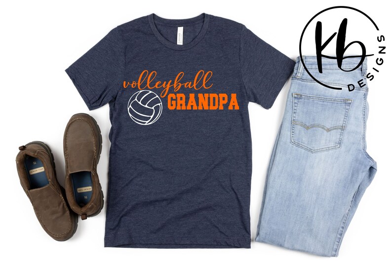 K&ouml;nnte beinhalten: Ein marineblaues T-Shirt mit dem Text "volleyball GRANDPA" in orangefarbener und wei&szlig;er Schrift. Neben dem Text befindet sich eine wei&szlig;e Volleyballgrafik.