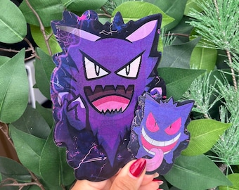 May include: Two purple stickers featuring the character Gengar. The larger sticker shows a jagged, dark purple Gengar with a wide, toothy grin and pointed ears. The smaller sticker depicts a rounder Gengar with pink eyes and a long, protruding tongue.
