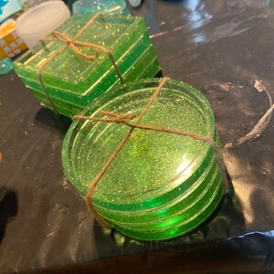 Puede incluir: Conjunto de cuatro posavasos de purpurina verde con una envoltura de cuerda r&uacute;stica. Los posavasos son redondos y tienen un acabado brillante y brillante.
