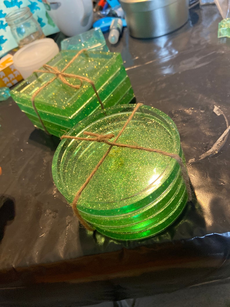 Puede incluir: Conjunto de cuatro posavasos de purpurina verde con una envoltura de cuerda r&uacute;stica. Los posavasos son redondos y tienen un acabado brillante y brillante.