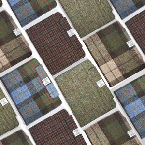 Puede incluir: Una variedad de cuadernos de tweed en varios patrones y colores, incluyendo cuadros, espiga y texturas lisas. Cada cuaderno tiene una pequeña etiqueta blanca. La paleta de colores incluye tonos de verde, azul, marrón y beige.