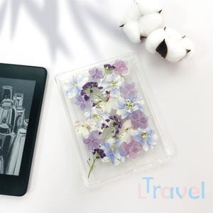 May include: A clear plastic case with a pressed flower design. The flowers are in shades of purple, blue, and white.