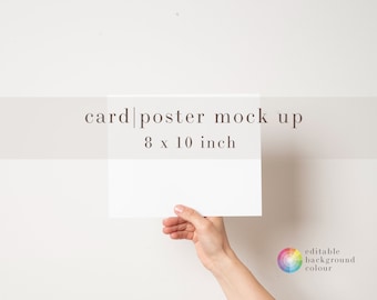 May include: A hand holds a blank white card or poster mockup against a white wall. The card is 8 x 10 inches. The text "card|poster mock up 8 x 10 inch" is visible at the top of the image.
