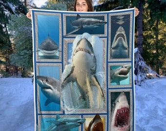 May include: A blue and white fleece blanket with a collage of images of sharks in different poses. The sharks are framed in silver and blue frames.