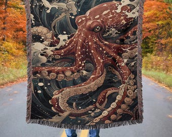 Op de afbeelding: Een geweven tapijtdeken met een gedetailleerde illustratie van een octopus met wervelende golven op de achtergrond. De octopus is afgebeeld in tinten rood, bruin en wit, met ingewikkelde details op zijn tentakels.