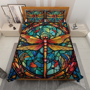 May include: A stained glass style dragonfly duvet cover with a large dragonfly in the center. The dragonfly is surrounded by a circular stained glass pattern in shades of blue, green, yellow, orange, and red. The duvet cover is made of soft, comfortable fabric and is perfect for adding a touch of whimsy to any bedroom.