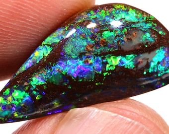 May include: A teardrop-shaped black opal with a dark brown base and iridescent green, blue, and purple flashes.