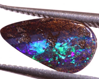May include: A teardrop-shaped opal gemstone with a brown matrix and iridescent blue, green, and purple flashes.