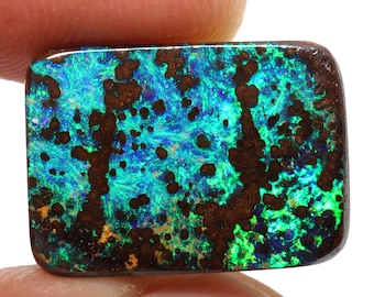 May include: A rectangular piece of opal with a dark brown matrix and a vibrant blue, green, and purple iridescent pattern.
