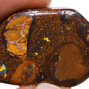 May include: A polished, natural opal gemstone with a dark brown base color. The opal features vibrant flashes of color, including yellow, blue, and green, within its matrix. The stone has a smooth, rounded shape and a glossy surface.