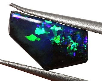 May include: A dark blue, green, and purple opal gemstone with a black background. The opal is held in tweezers.