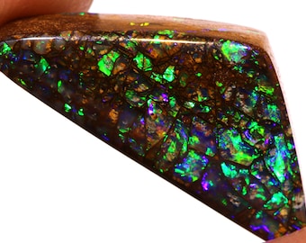 May include: A triangular piece of opal with a dark brown matrix and iridescent green, blue, and purple flashes.