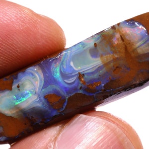 May include: A rectangular boulder opal gemstone featuring a dark brown ironstone matrix with vibrant, swirling veins of iridescent blue, green, and white opal material that catch the light with a polished, smooth surface finish.