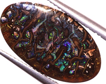 Pode incluir: Um cabochão de opala marrom, verde e azul com um padrão único e espiralado. A opala está engastada em uma configuração prateada.