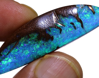 Op de afbeelding: Een blauwgroene opaal cabochon met een donkerbruine ijzerstenen achterkant. De opaal heeft een heldere, iriserende glans.