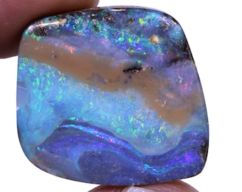 May include: A blue, green, and brown opal gemstone with a swirling pattern. The opal is cut into a rectangular shape with rounded edges.