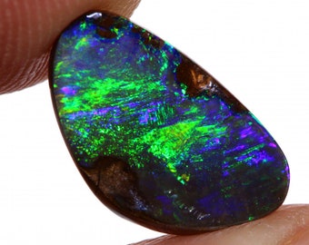 May include: A dark green, blue, and purple opal gemstone with a black backing. The opal is oval shaped and has a smooth, polished surface.