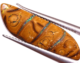 May include: A brown and gold opal cabochon with iridescent blue and green flashes. The opal is held in tweezers.