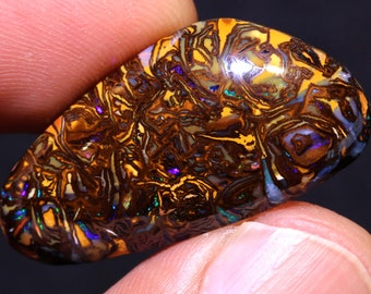 May include: A vibrant, multi-colored opal with a swirling pattern of brown, yellow, blue, and purple hues. The opal is a smooth, oval shape and has a glossy finish.