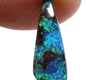 May include: A teardrop-shaped black opal gemstone with green and blue iridescent flashes.
