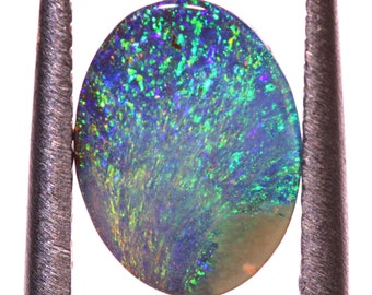 Può includere: Una gemma di opale verde, blu e viola vibrante con un motivo a spirale. L'opale è di forma ovale ed è tenuta in posizione da due pinzette metalliche.