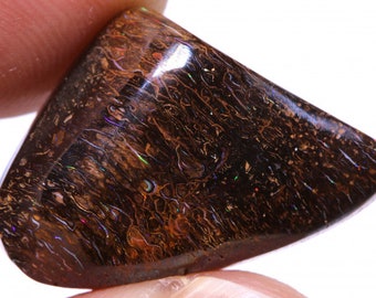 May include: A dark brown, iridescent opal with a rough, natural shape. The opal has a unique pattern of swirling colors, including shades of blue, green, and red.