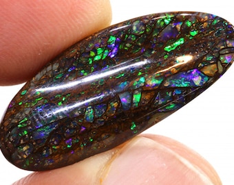 May include: A close-up of a dark brown oval-shaped opal with green, blue, and purple iridescent flashes. The opal is set in a polished silver setting.