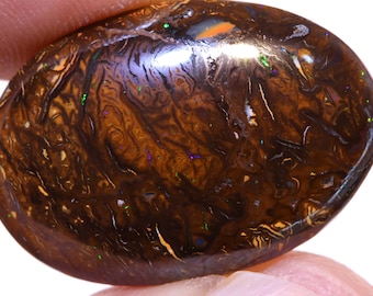 May include: A brown opal gemstone with a swirling pattern of iridescent colors, including green, blue, and purple.
