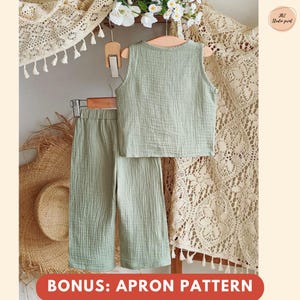 Puede incluir: Un conjunto infantil de dos piezas verde claro, que consta de una camiseta sin mangas y pantalones de pernera ancha, cuelga de una percha de madera. El conjunto est&aacute; hecho de una tela texturizada. Las palabras "BONUS: APRON PATTERN" se muestran en una pancarta roja en la parte inferior.