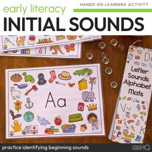 Puede incluir: Actividad educativa para la alfabetización temprana con el texto "Initial Sounds." La imagen muestra hojas de alfabeto con ilustraciones y la letra "Aa." Hojas adicionales muestran imágenes para identificar los sonidos iniciales. El texto "practice identifying beginning sounds" también es visible.