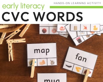 May include: A set of CVC word cards with real-life photos. The cards feature the words "map", "mug", and "fan". Each card has three squares with a picture in each square. The pictures are a map, a mug, and a fan. There are also wooden clothespins on the table.
