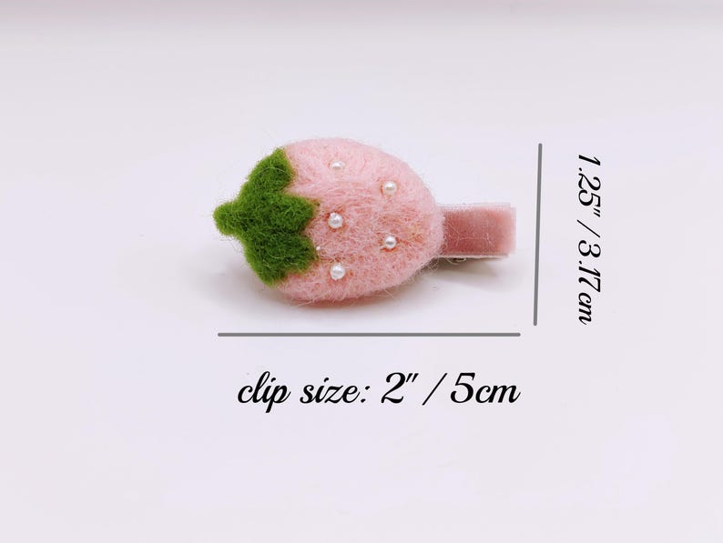 Puede incluir: Una pinza para el pelo de fresa de fieltro rosa con detalles de perlas blancas y una hoja de fieltro verde. La pinza mide 3,17 cm de largo y el tama&ntilde;o de la pinza es de 5 cm.
