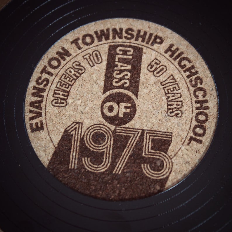 May include: A brown cork coaster with a black vinyl record design. The coaster features the text "Evanston Township High School" and "Cheers to the Class of 1975" with the words "Class of" in a circle. The text "50 Years" is also included.
