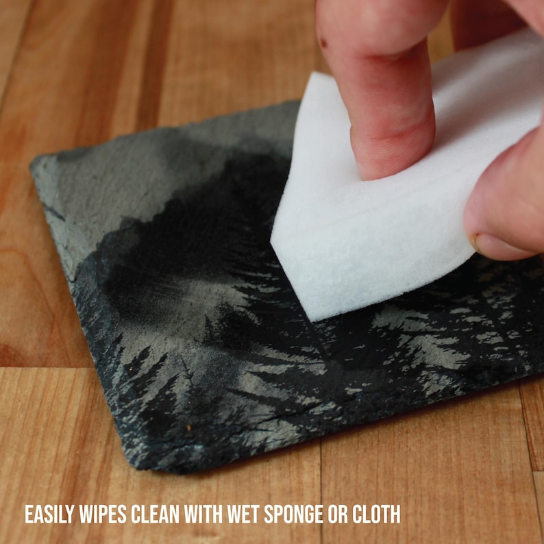 Slate stone drink coaster featuring graphic of a foggy mountain scene etched onto the top surface of the coaster