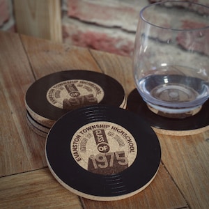 May include: Four black and brown cork coasters with a record design. The coasters feature the text "Evanston Township High School" and "Class of 1975".