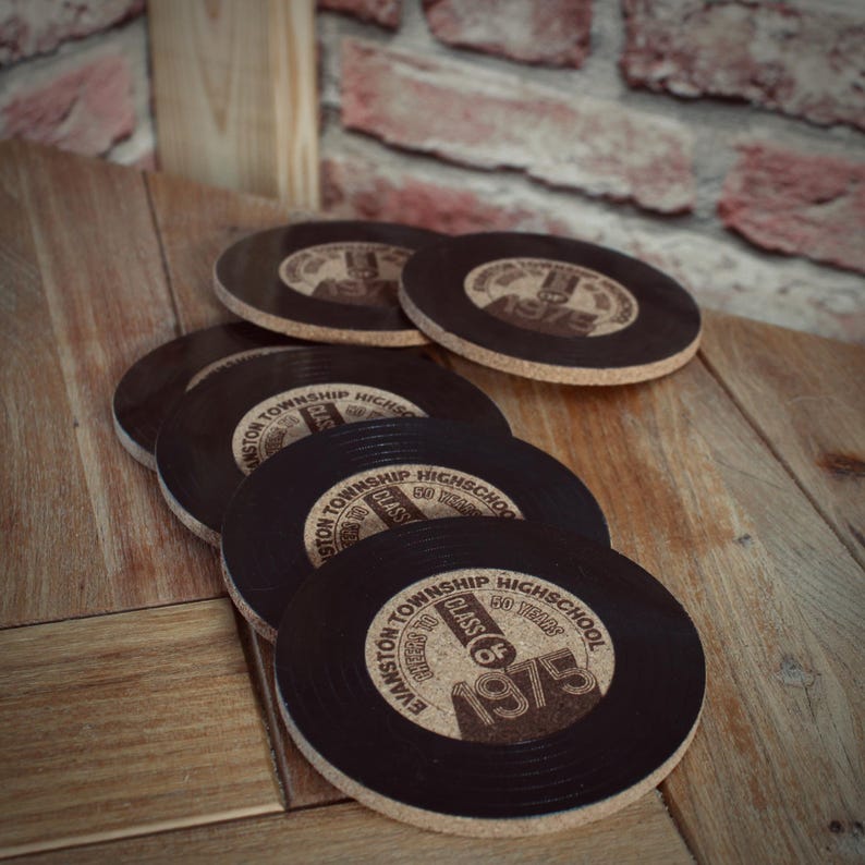May include: Set of six black and brown round coasters with a cork backing. Each coaster features a vintage record design with the text "Evanston Township High School Class of 1975".