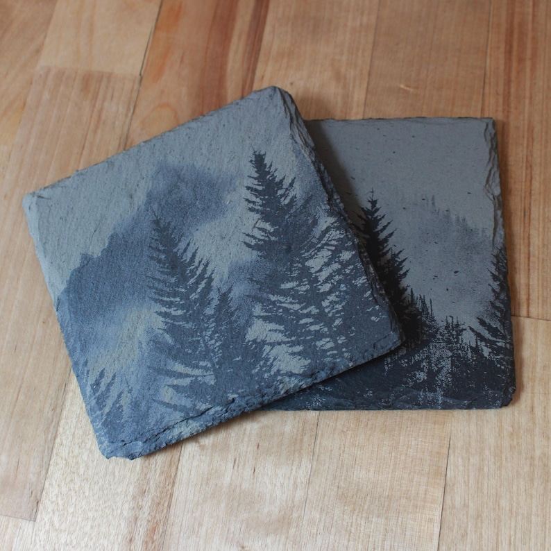Slate stone drink coaster featuring graphic of a foggy mountain scene etched onto the top surface of the coaster