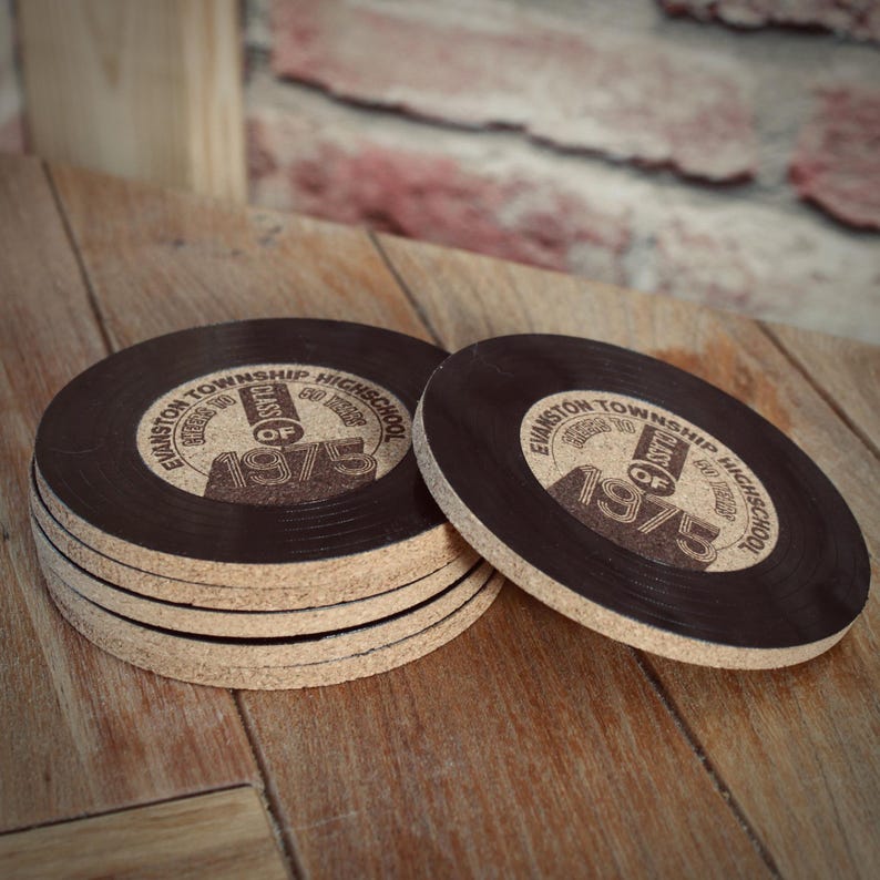 May include: Six brown cork coasters with a black vinyl record design. The coasters feature the text "Evanston Township High School" and "Class of 1975".