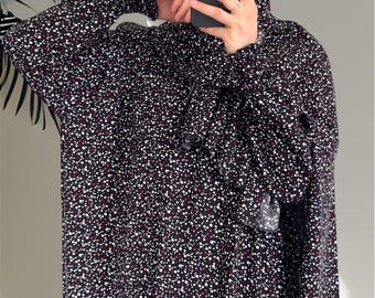 May include: A black and white floral print garment with a matching head covering. The fabric has a pattern of small white and burgundy dots. The sleeves are long and loose, and the garment appears to be a dress or tunic.