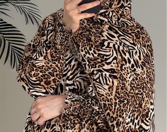 May include: A matching set featuring a hijab and a long-sleeved top, both adorned with a brown and black animal print. The fabric has a zebra and leopard pattern. The sleeves have a gathered cuff detail.