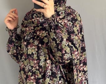 May include: A black floral print outfit, including a head covering and long-sleeved top. The pattern features green, pink, and white flowers. The sleeves are gathered at the wrists.