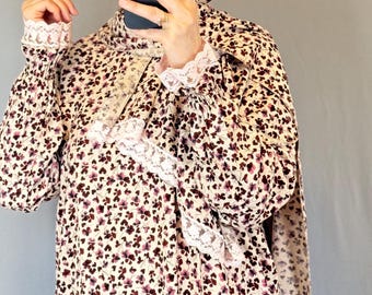 May include: Cream-coloured floral print outfit, including a head covering and long-sleeved dress. The outfit features a pattern of small burgundy flowers. White lace trim accents the cuffs and neckline.