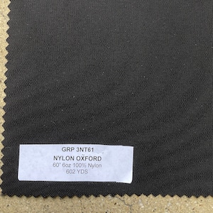 May include: A black nylon oxford fabric swatch with a white label that reads "GRP 3NT61 NYLON OXFORD 60" 6oz 100% Nylon 602 YDS".