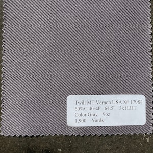 May include: A close-up of a grey twill fabric swatch with a white label that reads "Twill MT.Vernon USA S# 17984 60%C 40%P 64.5" 3x1LHT Colour Grey 9oz 1,900 Yards".
