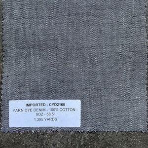 May include: A gray denim fabric swatch with a white label that reads "IMPORTED - CYD2160 YARN DYE DENIM - 100% COTTON - 9OZ - 58.5" 1,395 YARDS"